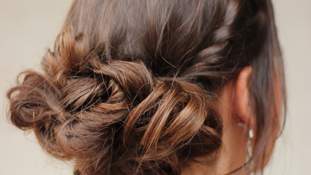Boufant Updo Header by Amy Shaughnessy from Getty Images women with long brown hair in salon with rear view of bouffant updo formal hairstyle