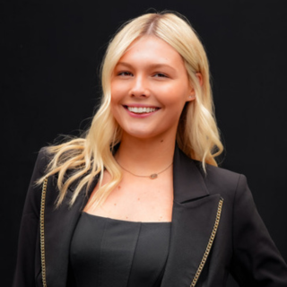Natalie Staff Quote Image Salon Baci Stylist Natalie posing for head shot photo black background beautiful long blond hair and smiling