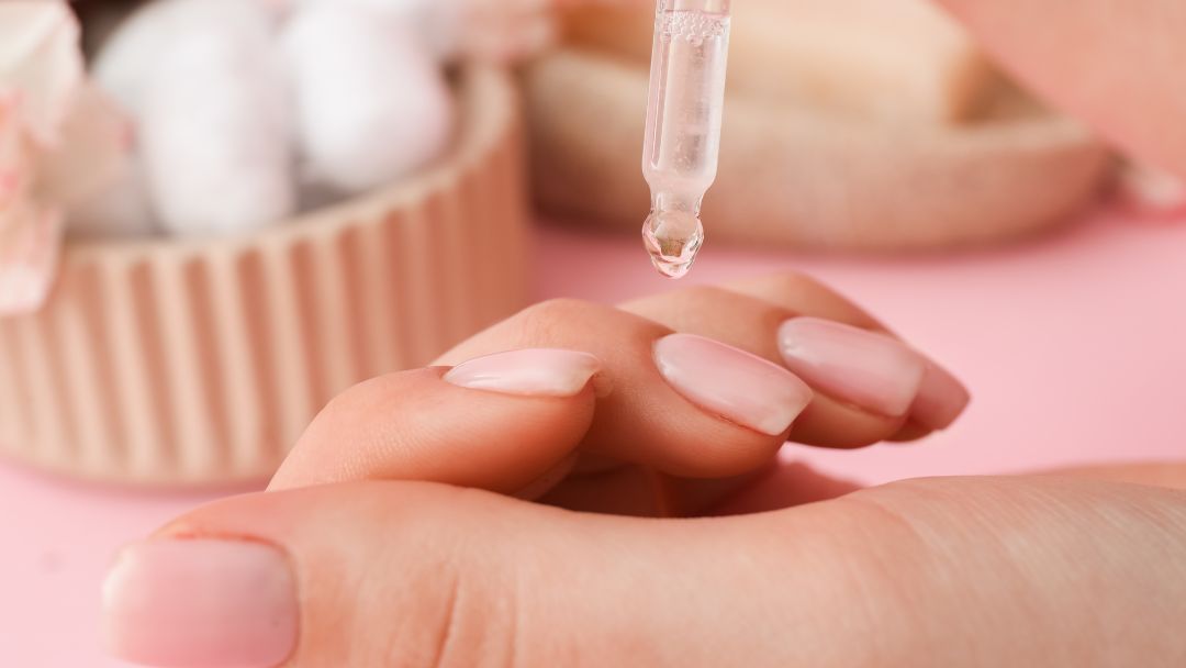 Cuticle Health by pixelshot Image of women's hand showing healthy nails and an eyedropper applying oil to cuticles