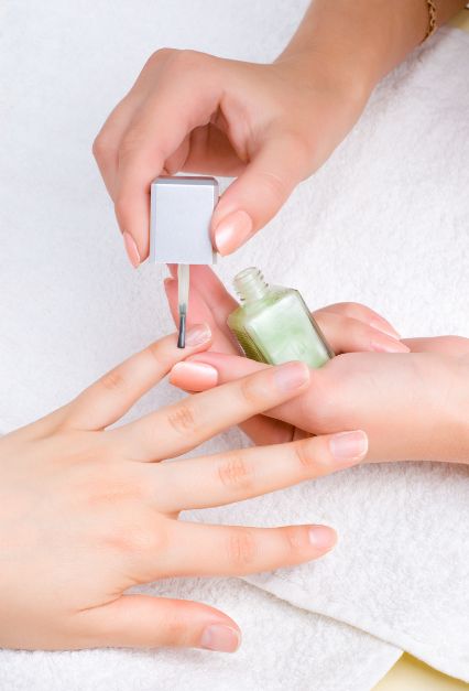 Close up picture o a women's hands and the hand of a manicurist applying  moisturizin gel to nails