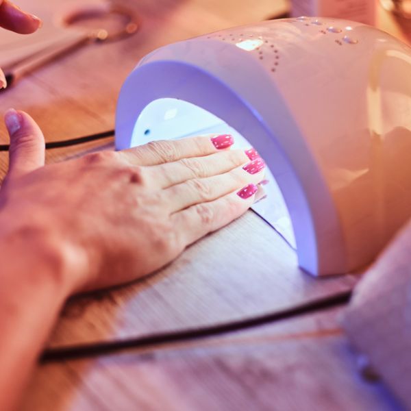 Image showing a close up of a salon customers hand with new red nail polish placed in the Infrared dryer.