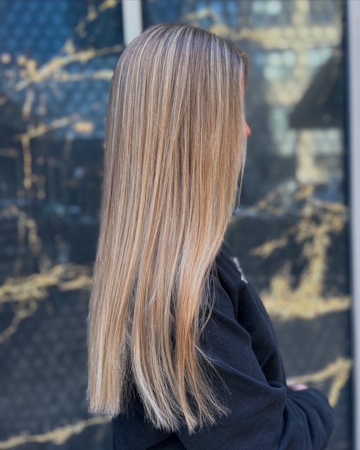 Young women with Balayage servie to creat long lasting results showing a head and shoulder side view with long medium blonde hair 