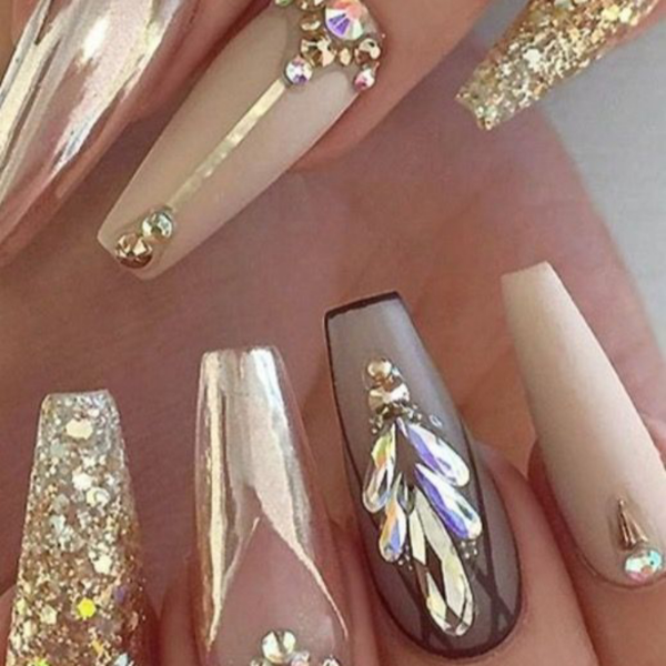 Close up of 3D nail polish on women's finger nails showing gold backgrounds and various costume jewelry glued for a dramatic look.