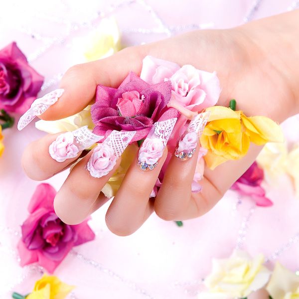 Close up of women's hand and wedding art nails with like pink base and shite floral art with hand holding pink and white flowers