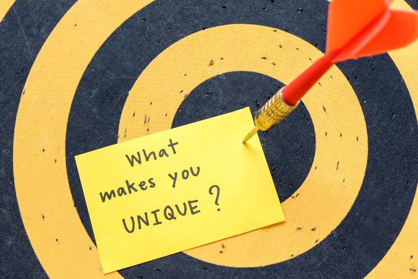 Graphic showing a black and yellow archer's target with a dart sticking in a post-it note titled, "What Makes You Unique?