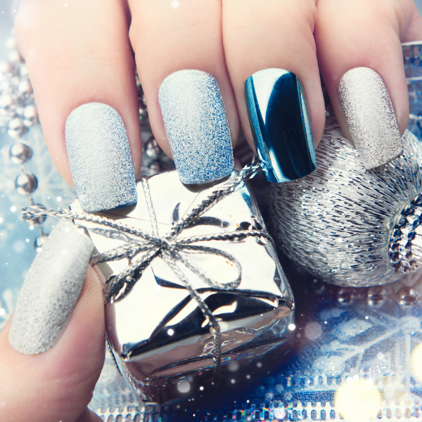 Close up of stunning Wedding Day nail art. Close up of the hand of the bride showing her nail art with fingers gently holding a small silver foil wrapped gift. The Nails are a soft speckled blue with the ring finger nail a reflective silver color.