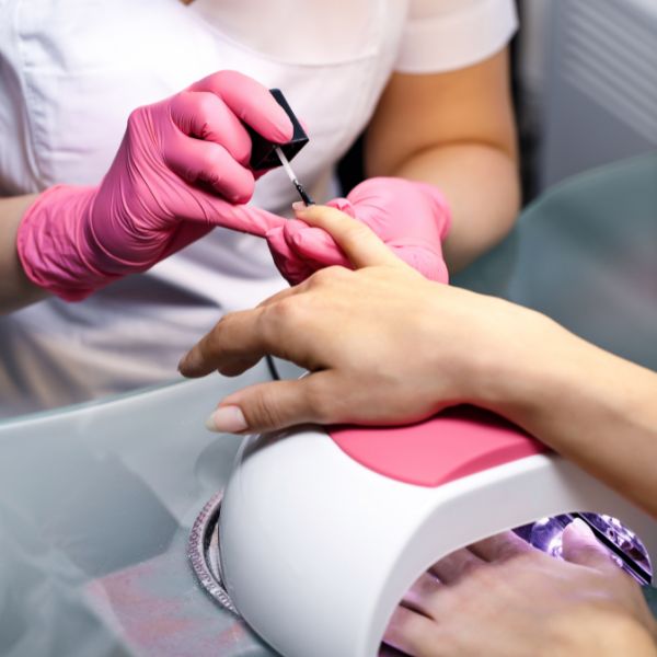 Close up of nail technician applying keratin treatment to women's nail for a stylish and healthy nails result.